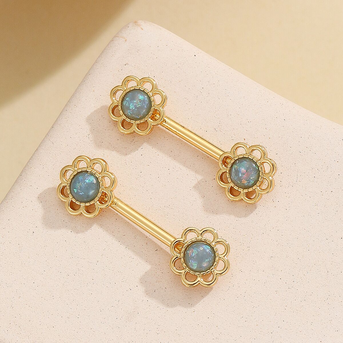 Unique teal blue shimmering flower fake nipple rings with gold accents.