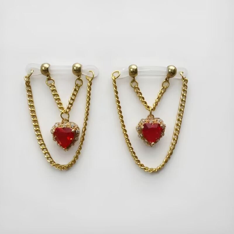 Non-piercing nipple clamps featuring ruby red teardrop crystal pendants and gold dangle chains on clear silicone loops, sold as a pair.