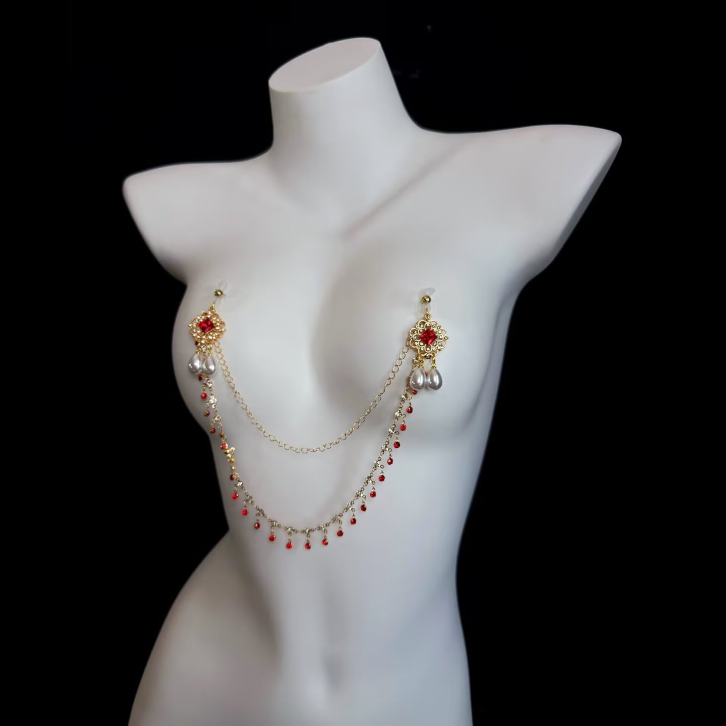 Non-pierced gold nipple chain jewelry featuring intricate vintage filigree motifs, red crystal studs, dual teardrop pearls, and soft suction caps.