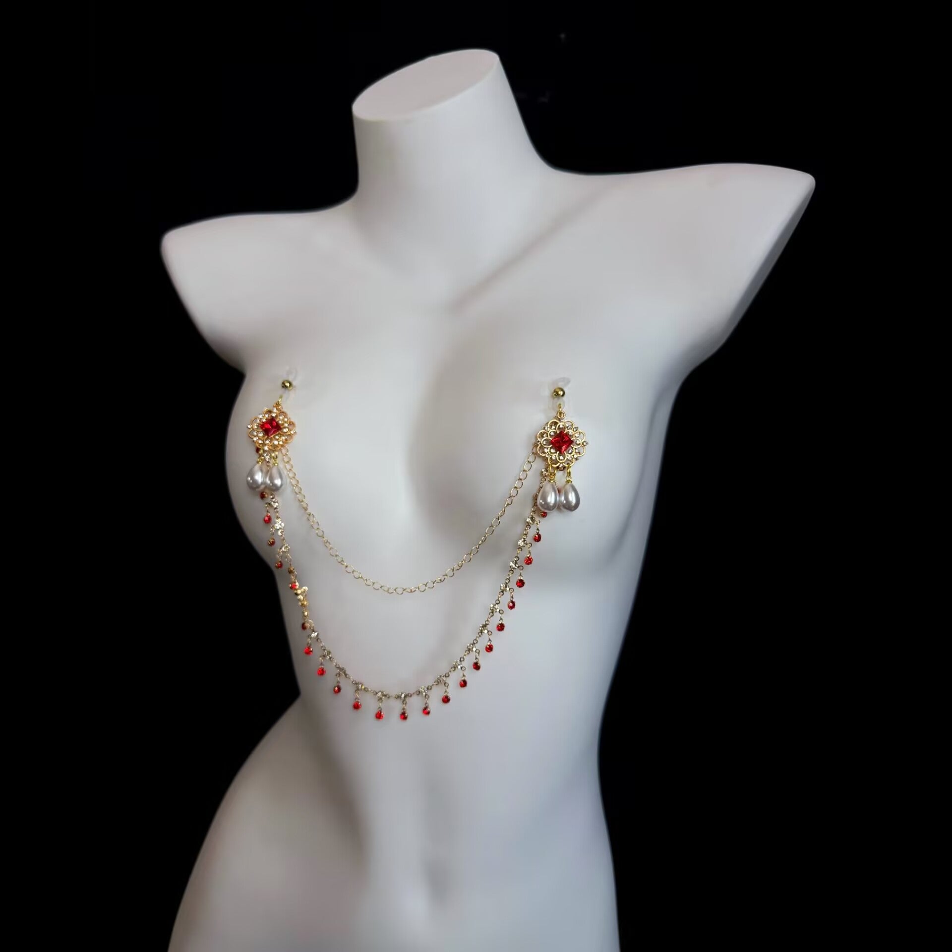 Non-pierced gold nipple chain jewelry featuring intricate vintage filigree motifs, red crystal studs, dual teardrop pearls, and soft suction caps.