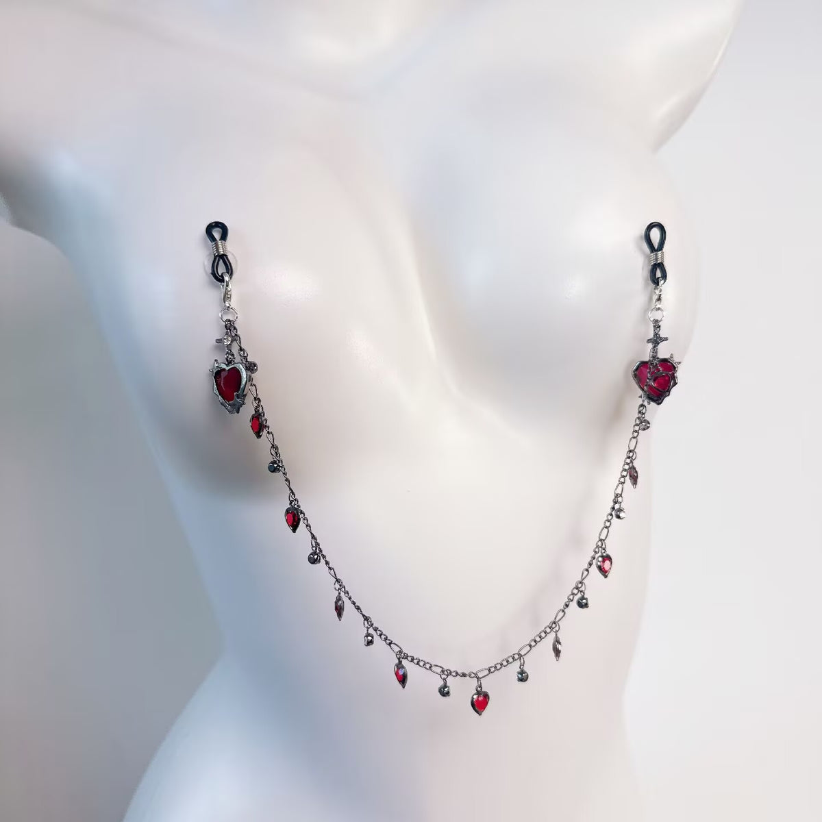 Close up of rubber-tipped non-pierced nipple clamps connected by a dangling red heart crystal chain