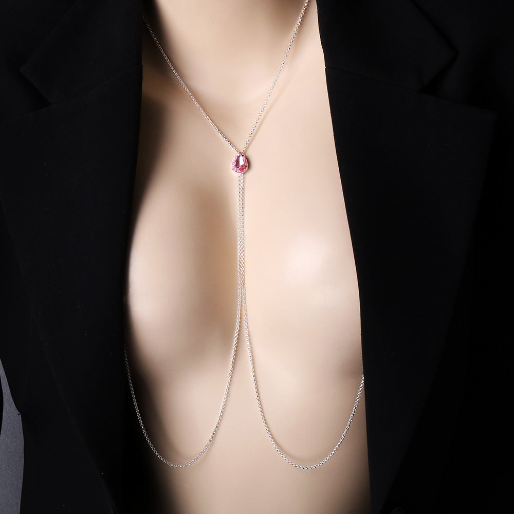 A model wearing a sexy silver non-piercing nipple chain necklace with a pink teardrop crystal underneath a deep-V black blazer, showcasing stylish and sensual female body jewelry.