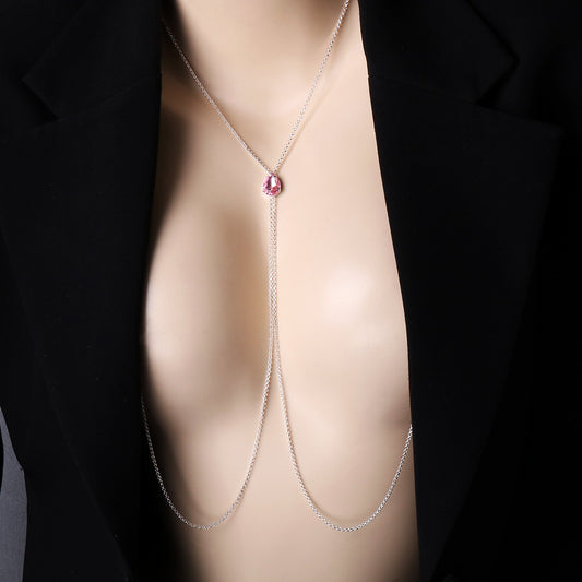 A model wearing a sexy silver non-piercing nipple chain necklace with a pink teardrop crystal underneath a deep-V black blazer, showcasing stylish and sensual female body jewelry.