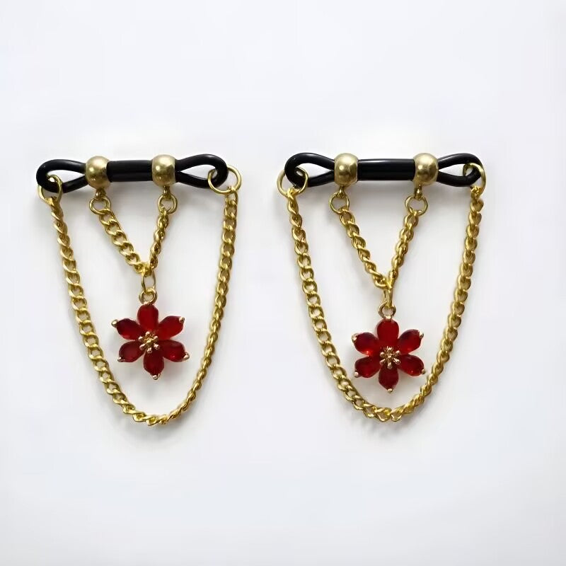 Non-piercing nipple clamps with ruby red crystal flower pendants suspended between curved gold drop chains.