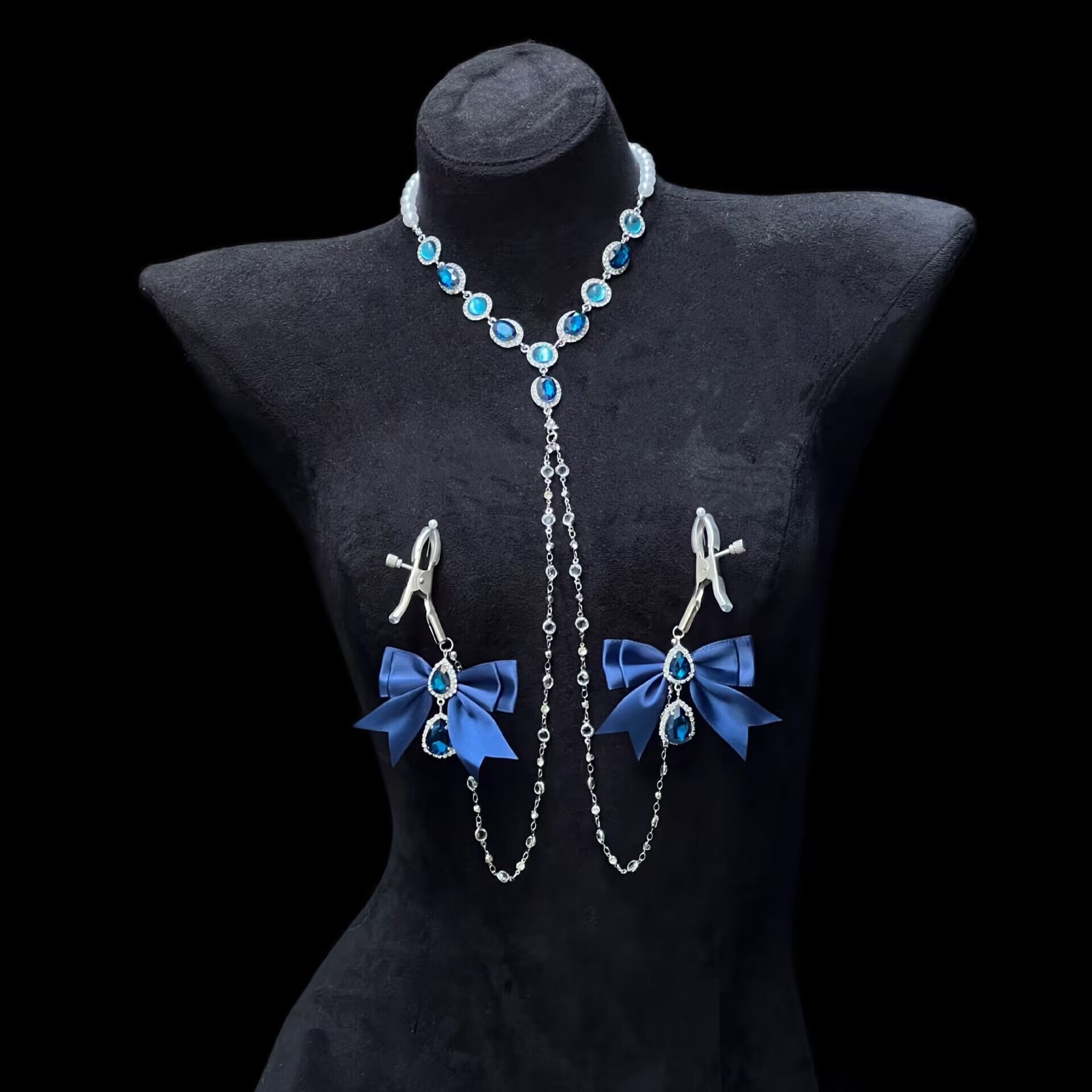 Front view of an elegant blue rhinestone necklace attached to matching non-piercing lingerie clamps on a black velvet torso mannequin.