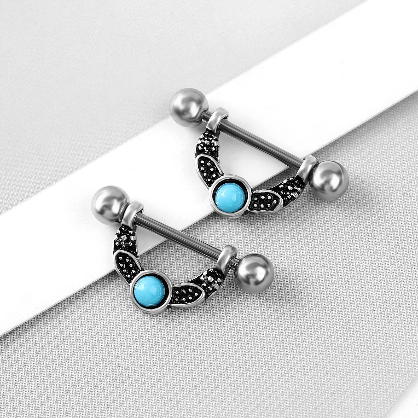 A pair of bohemian style nipple barbells with turquoise stones displayed on a clean white surface.