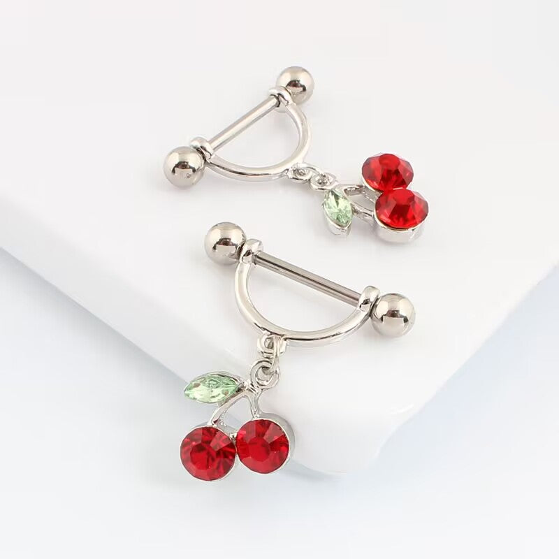 A pair of coquette aesthetic red cherry nipple piercing rings displayed together on a clean background.