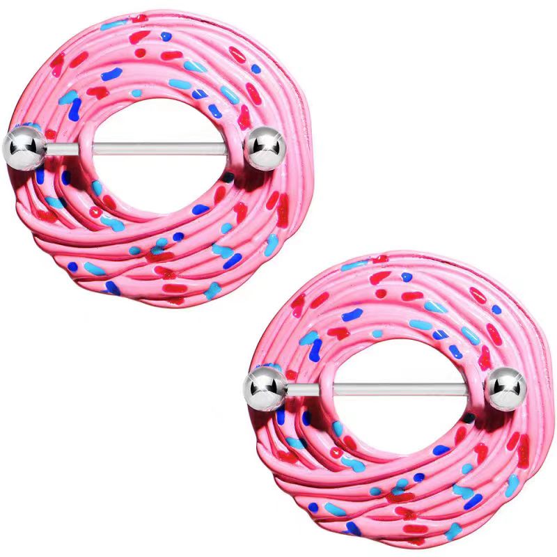 A pair of playful pink frosted donut nipple shields with colorful sprinkle details and metallic body piercing barbells, showcased from a top-down angle on a clean white background.