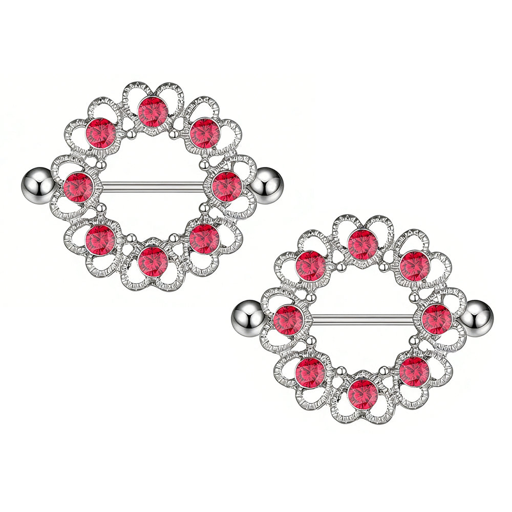 A pair of ornate silver nipple piercing shields with red gemstone accents for alternative fashion styling.