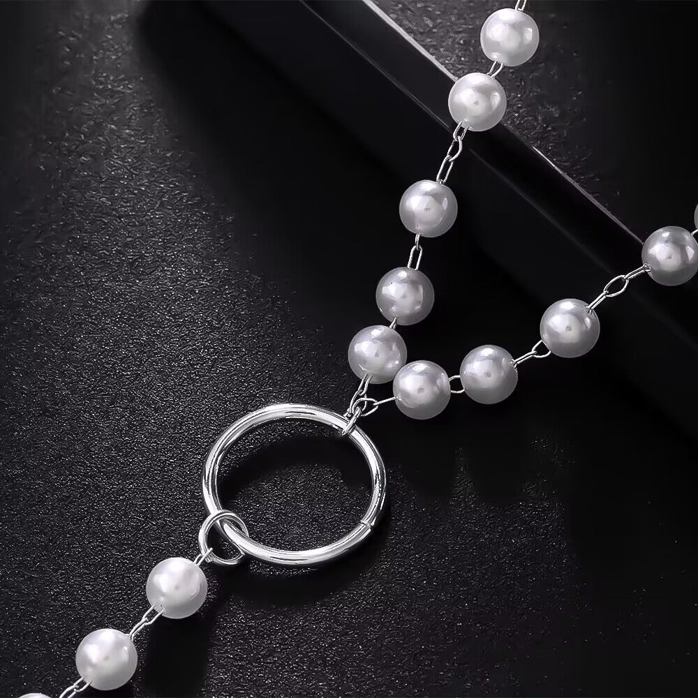 Close-up detail of smooth high-lustre ABS pearls linked to a polished metal O-ring connector.
