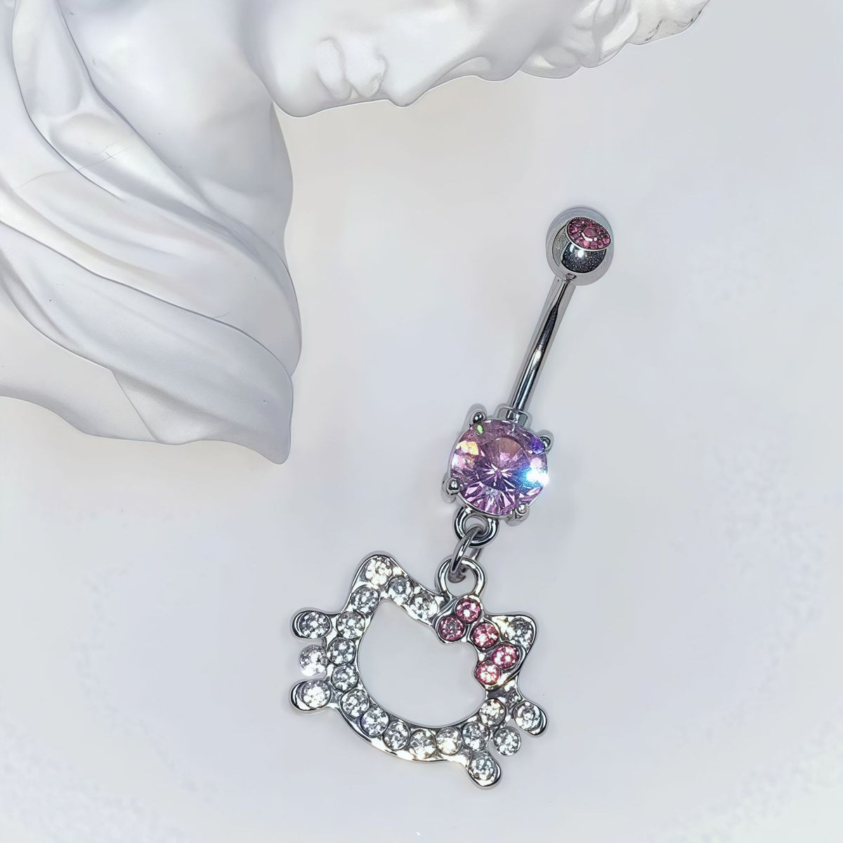 Single pink cat-and-bow navel ring with a prong-set centerpiece and a pink stone in the top ball beside a white ornament