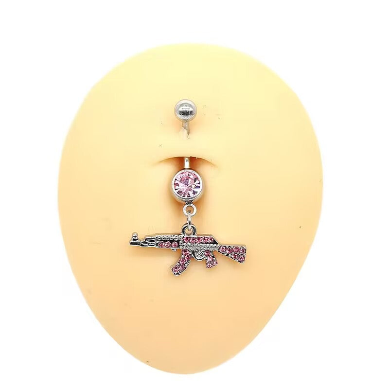 Sweet pink rhinestone paved AK47 gun navel ring piercing displayed on a body mannequin for y2k baddie look.