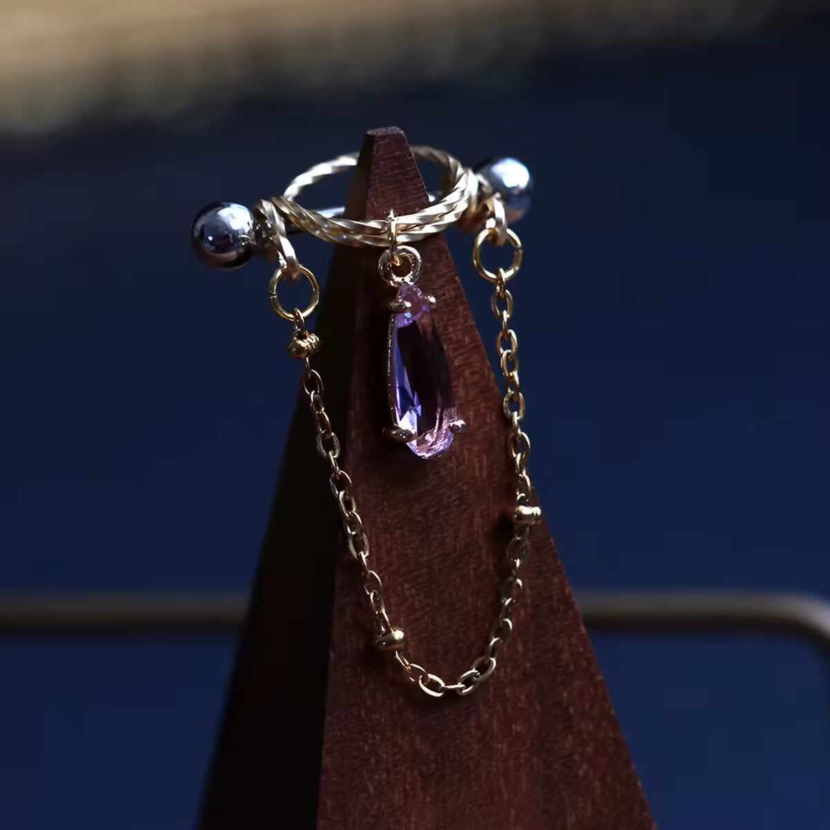 Purple amethyst style pear-cut CZ nipple ring barbell featuring halo shield and dangling chain.