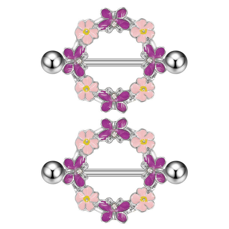 Close-up of a silver-tone nipple shield featuring purple enamel butterflies with crystal accents and pink flowers.