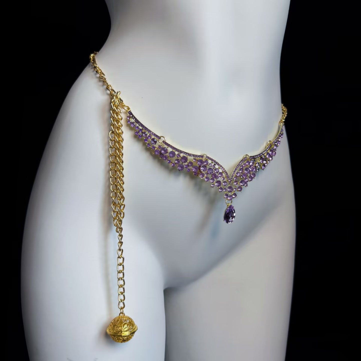 Gold waist chain belly jewelry with purple V-shaped crystal pattern and dangling golden filigree ball.