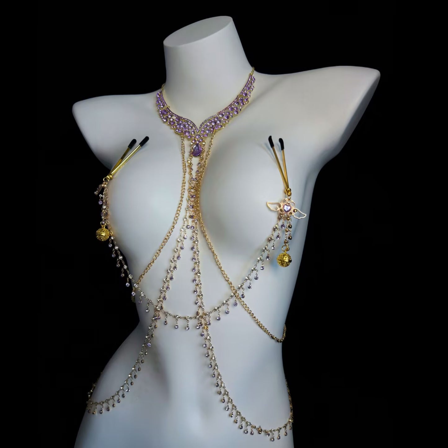 Close-up of gold chest harness chain connected to rubber-covered pressure nipple clamps with purple heart accents.