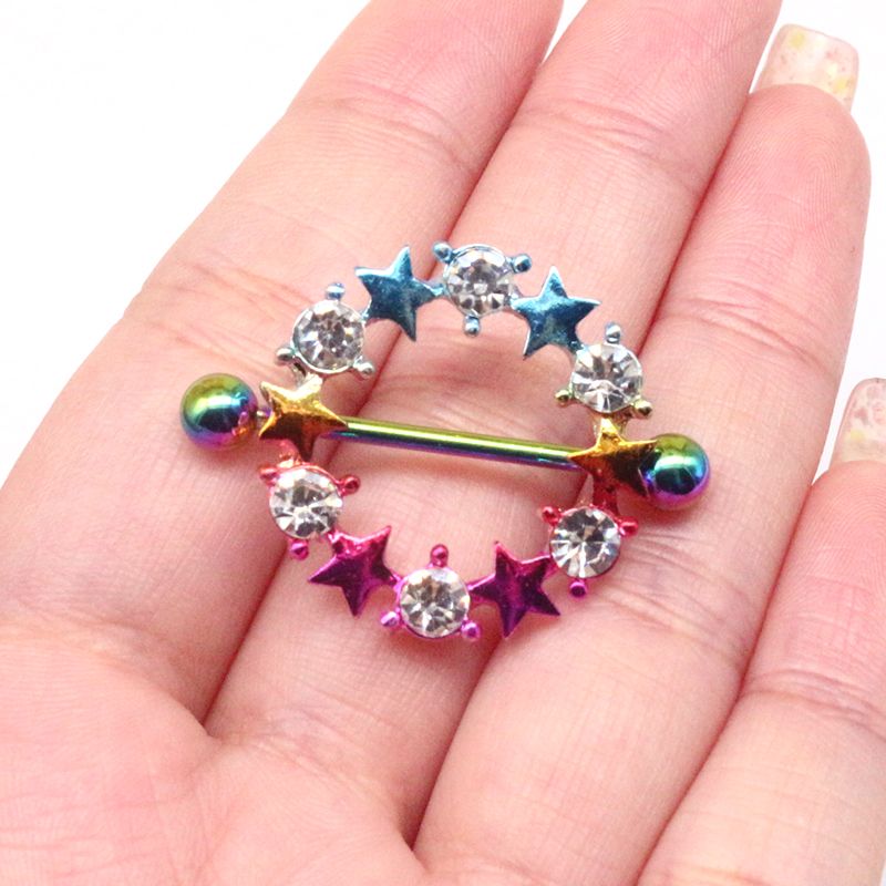 Real-life size comparison of a rainbow star nipple shield held in a person's hand.