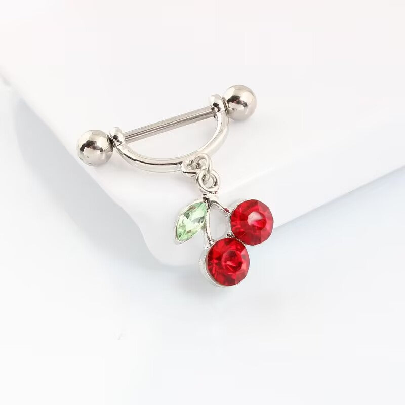 Angled close-up shot of a single dangling cherry nipple ring shield highlighting the glossy silver metal and red rhinestones.