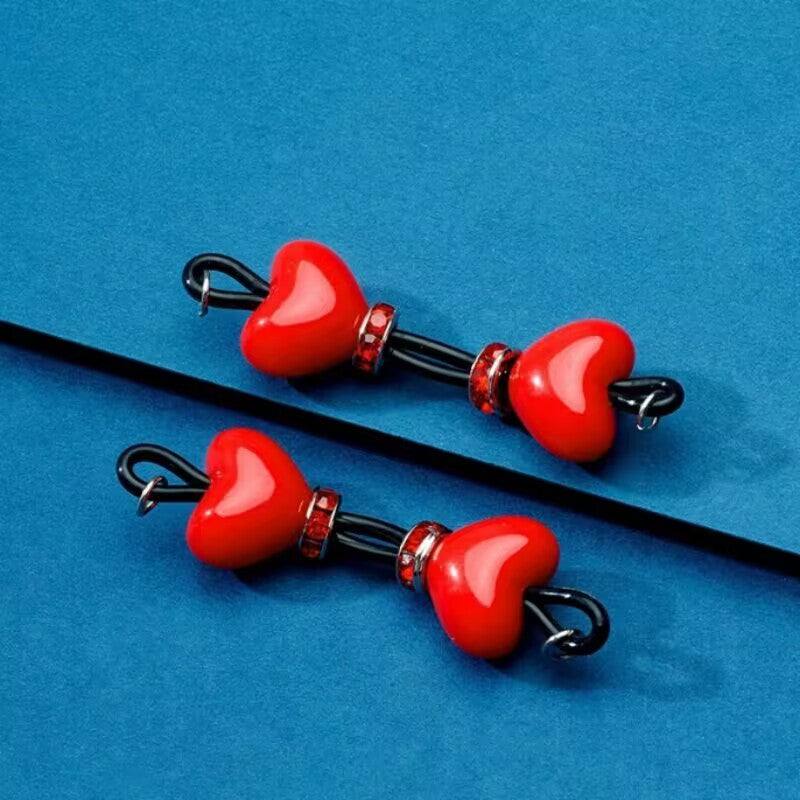 Pair of vibrant red heart non-piercing nipple rings with black silicone loops and red rhinestone accents for a bold body accent.
