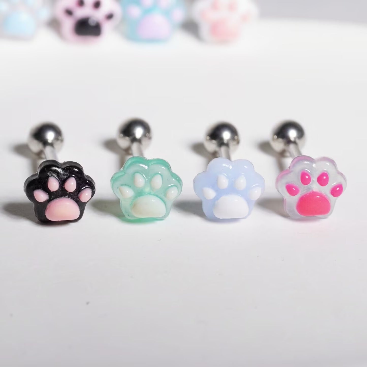 Collection of resin cat paw tongue rings showing black, green, light blue, and bright pink options