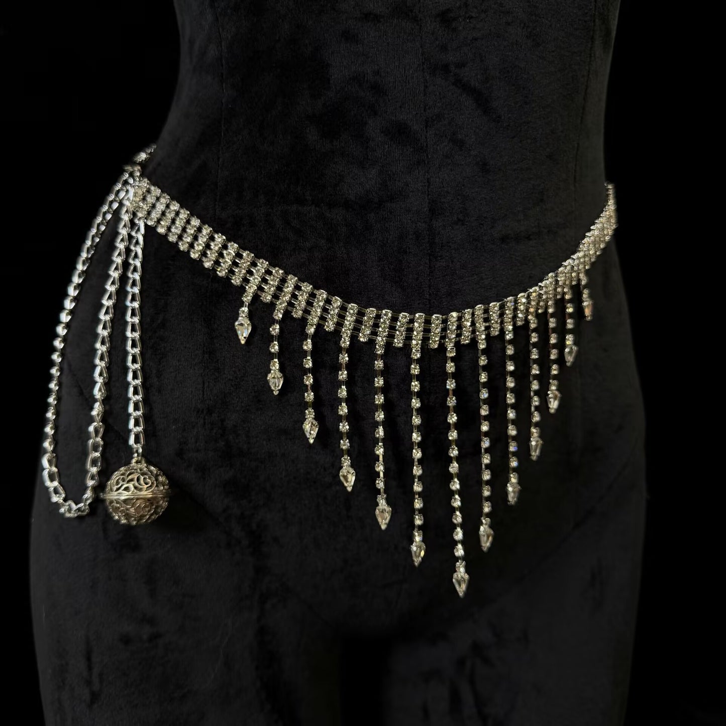 Sparkling silver rhinestone fringe waist chain belt featuring dangling crystal tassels and a hollow metal orb charm.