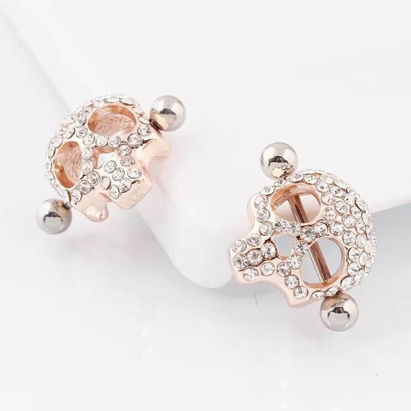Slanted view of rose gold skull-shaped nipple jewelry highlighting the brilliant shine of the crystals.