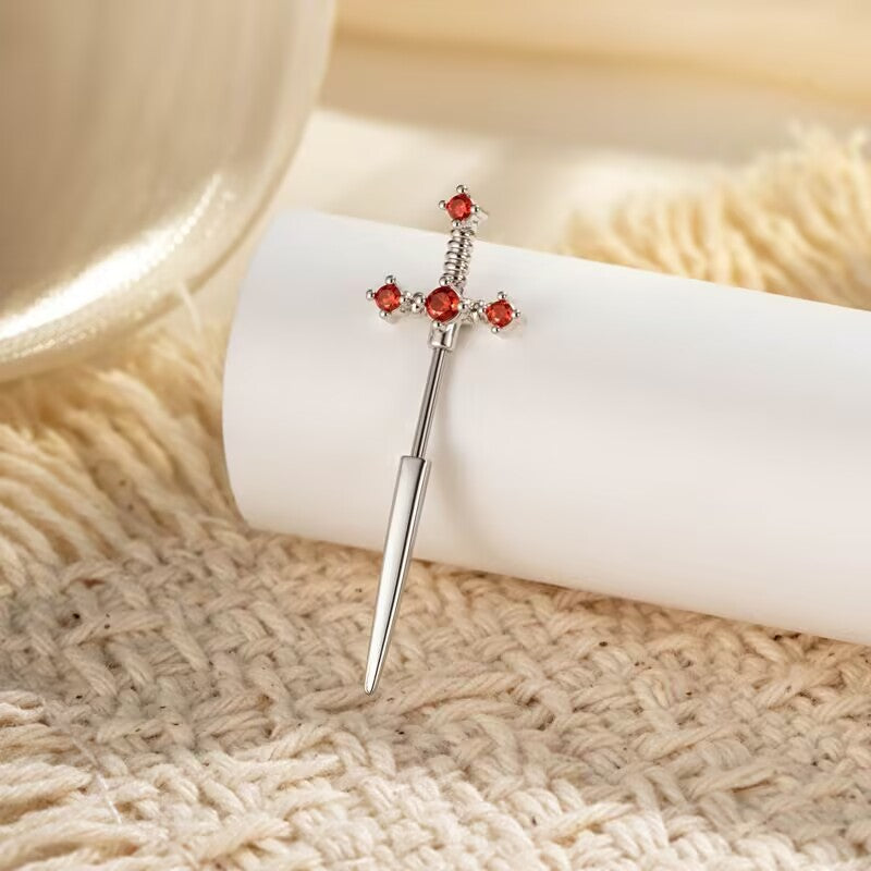 Silver dagger sword stud earring adorned with vibrant ruby red crystal gemstones.