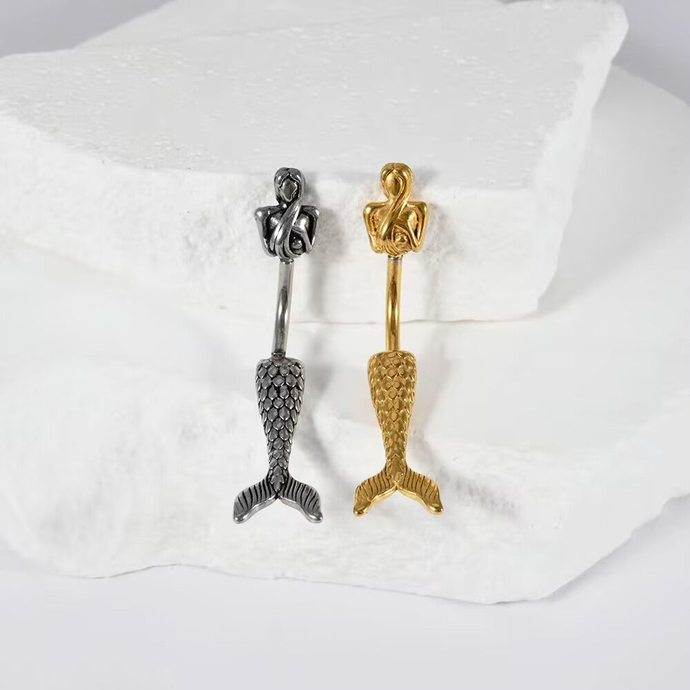 Silver and gold mermaid belly piercing barbells displayed side by side on a neutral background.