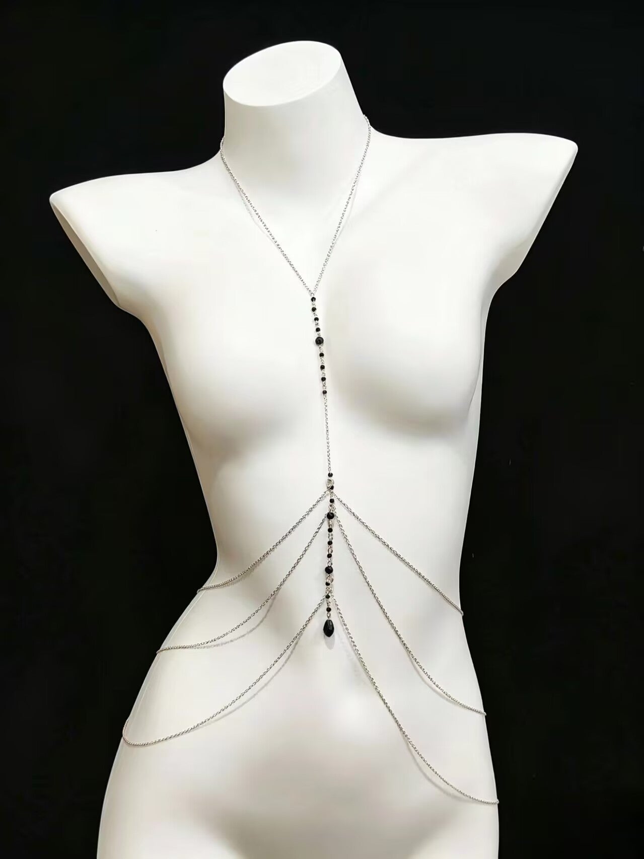 Silver layered chest and waist body chain displayed on a mannequin against a black background.