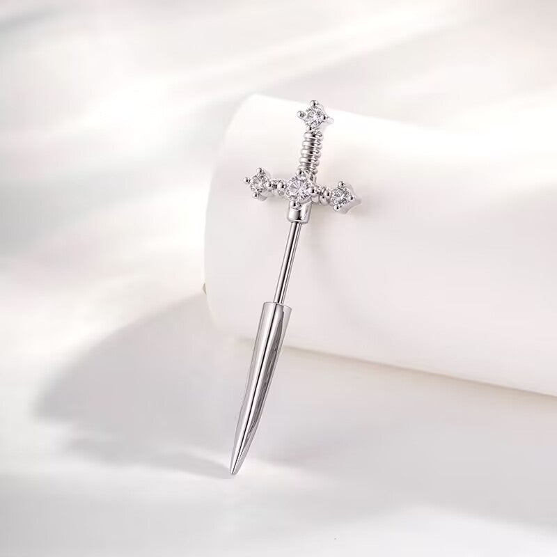 Vertical view of a silver dagger piercing stud featuring a crystal-encrusted hilt and sleek blade tip.