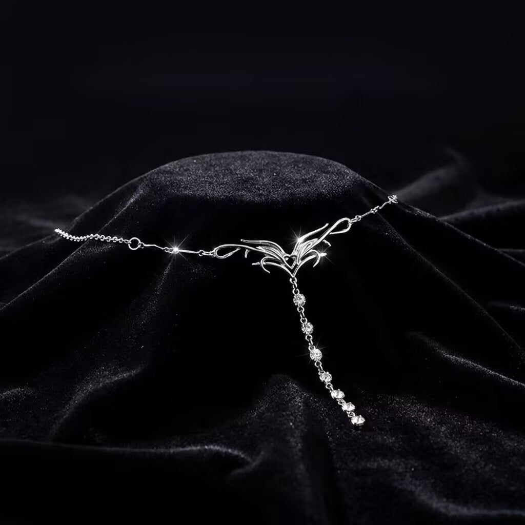 Close-up of silver flame waist chain with dangling rhinestones displayed on dark velvet fabric