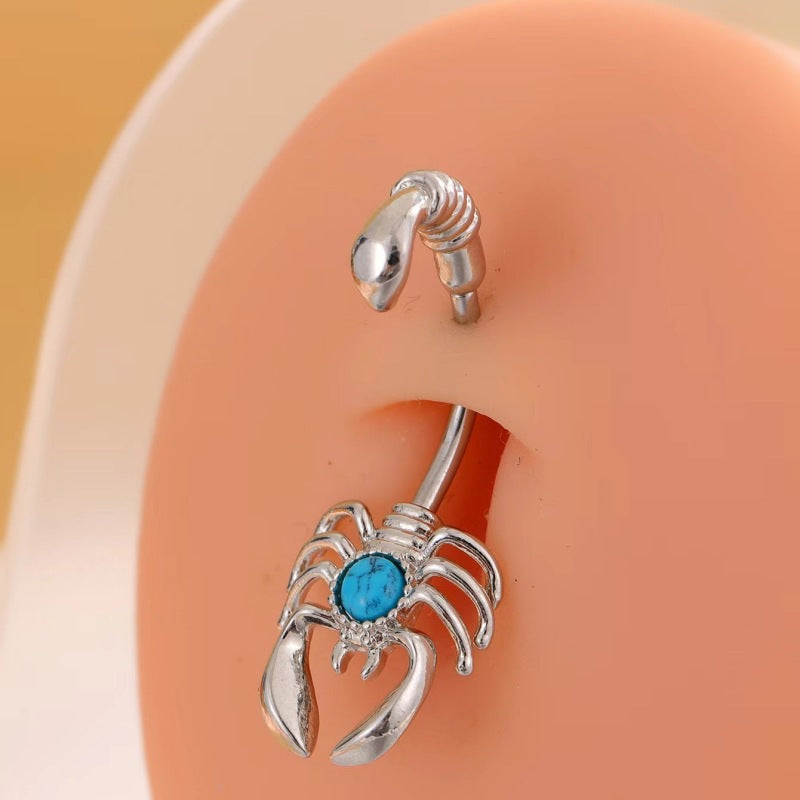 Single silver-tone scorpion belly button ring with a blue veined center shown on a piercing display model.