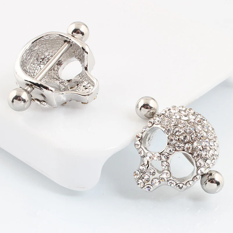 Front and back view of a crystal skull nipple piercing, showing the barbell bar and hollow shield design.