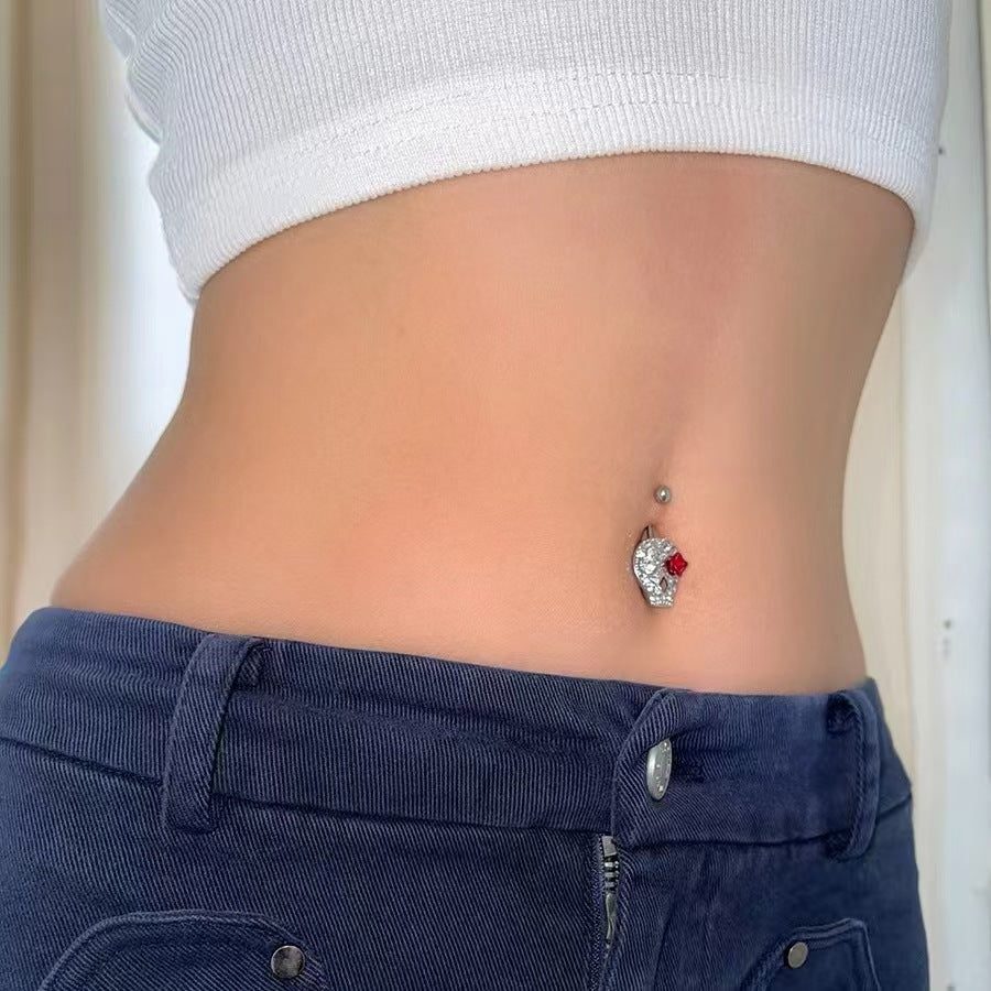 Close-up shot of a person wearing the sparkling skull and red rose belly button jewelry.