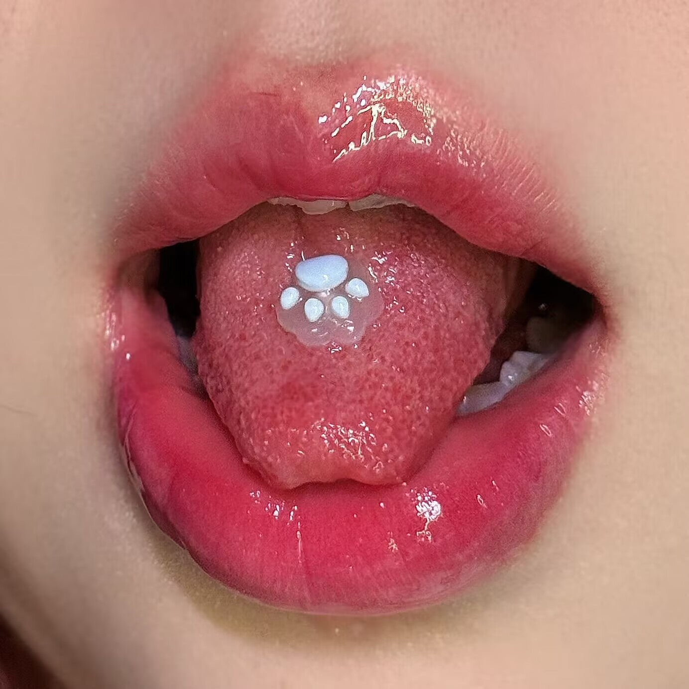 Girl wearing a soft sky blue resin cat paw tongue ring stud, dainty and aesthetic oral piercing accessory