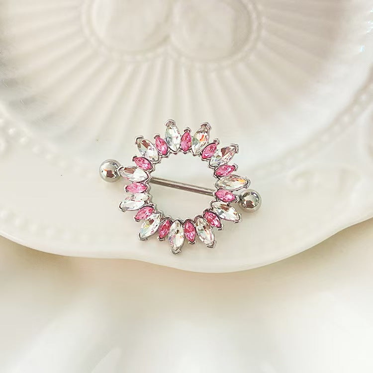 Lifestyle view of a sparkling pink marquise gemstone nipple ring resting on an elegant vintage white ceramic plate, catching natural light.