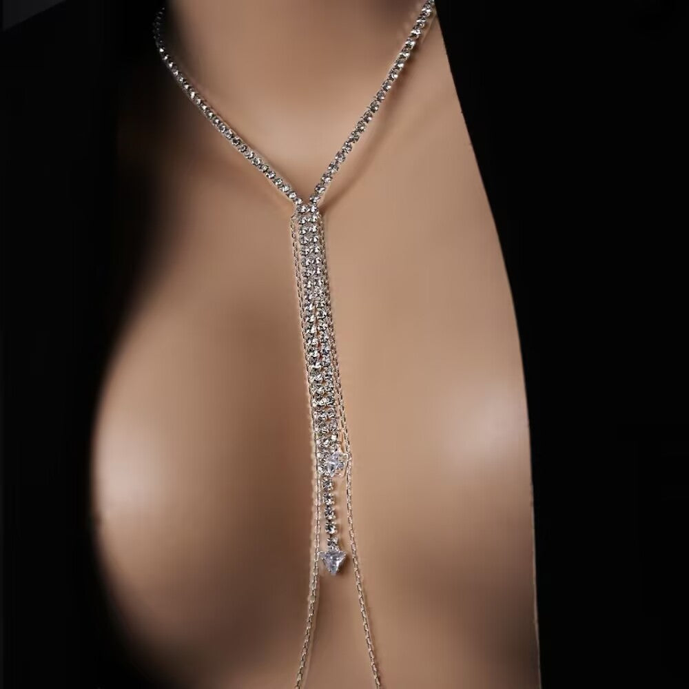Close-up of a female mannequin wearing a sparkling rhinestone Y-necklace body chain that extends down into a non-piercing nipple chain accessory, styled with a black blazer.