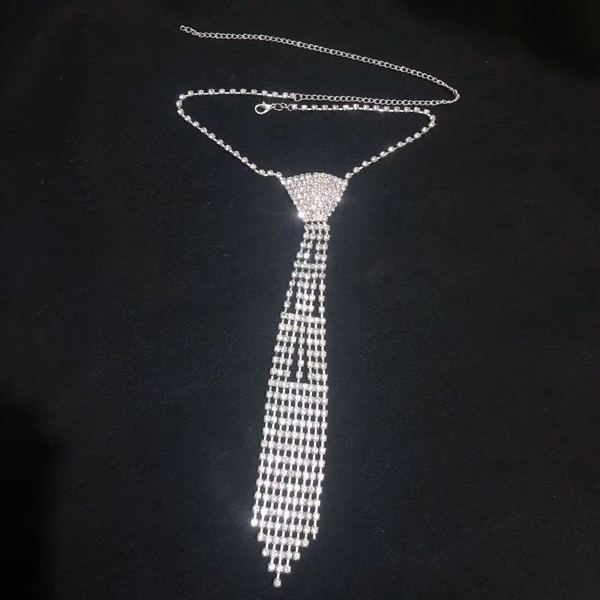 Dazzling silver crystal tie choker body chain with mesh layout displayed on black fabric.