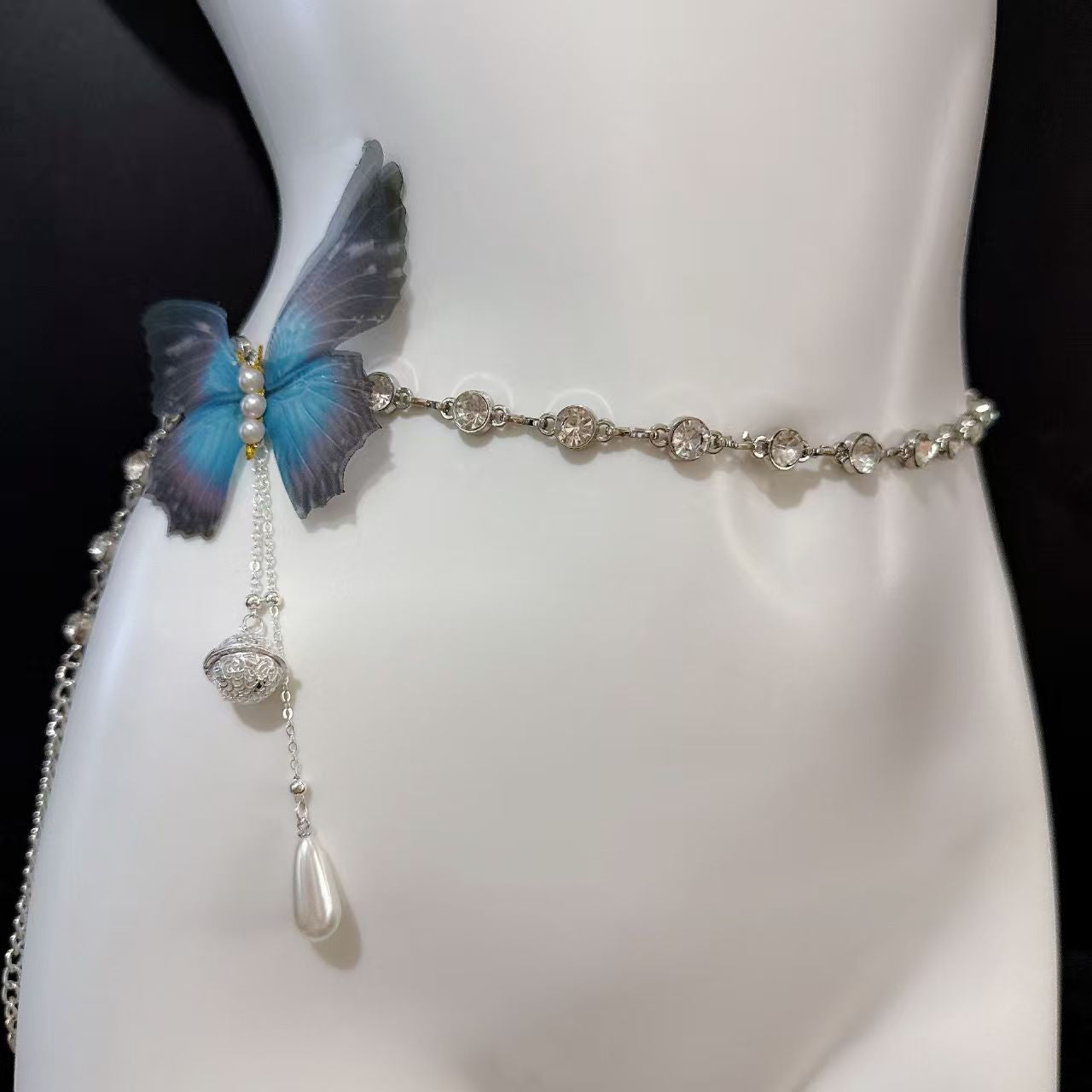 Sparkly rhinestone belly waist chain accented with a gradient blue butterfly charm and pearl dangle.