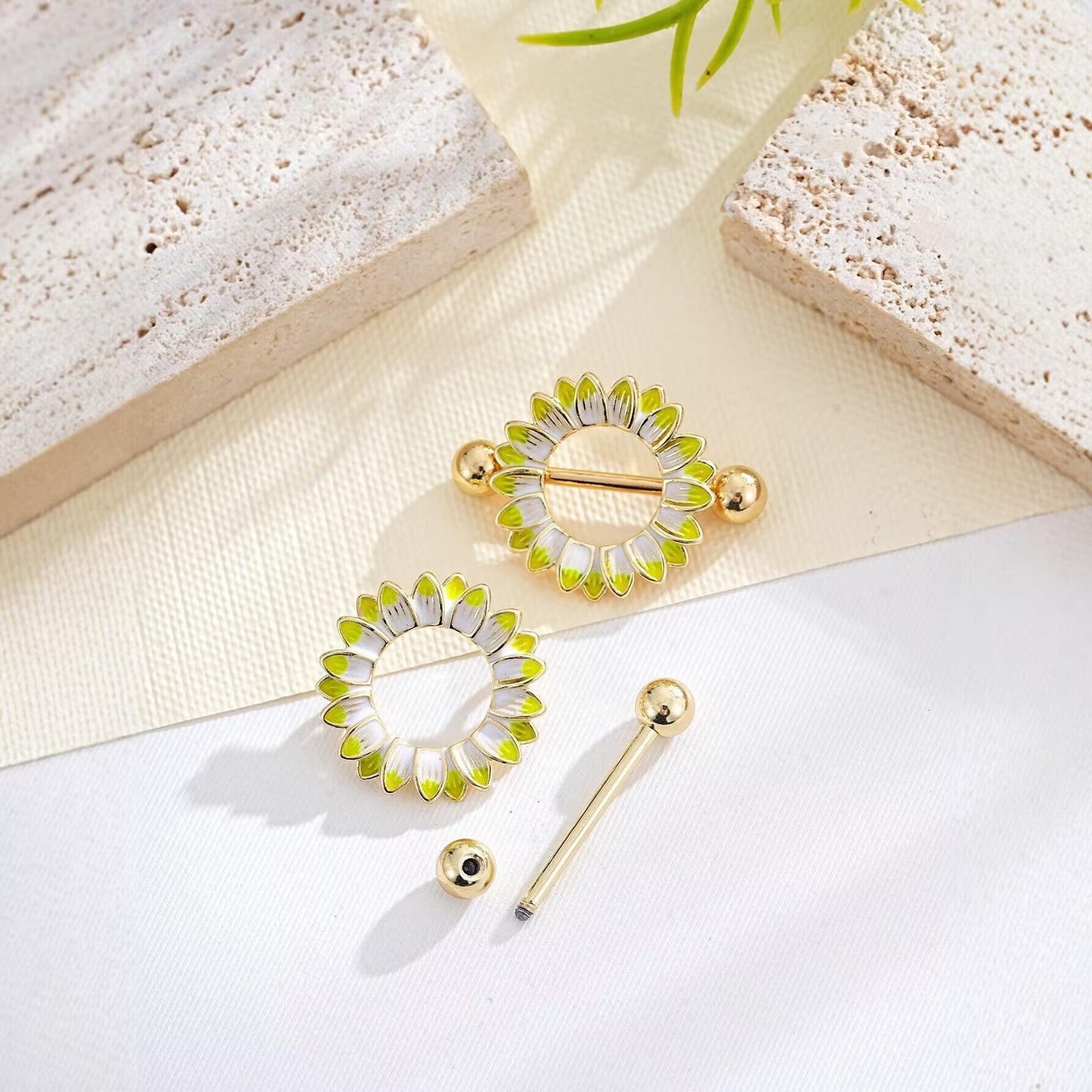 Disassembled sunflower nipple shield showing the floral ring and straight barbell components.