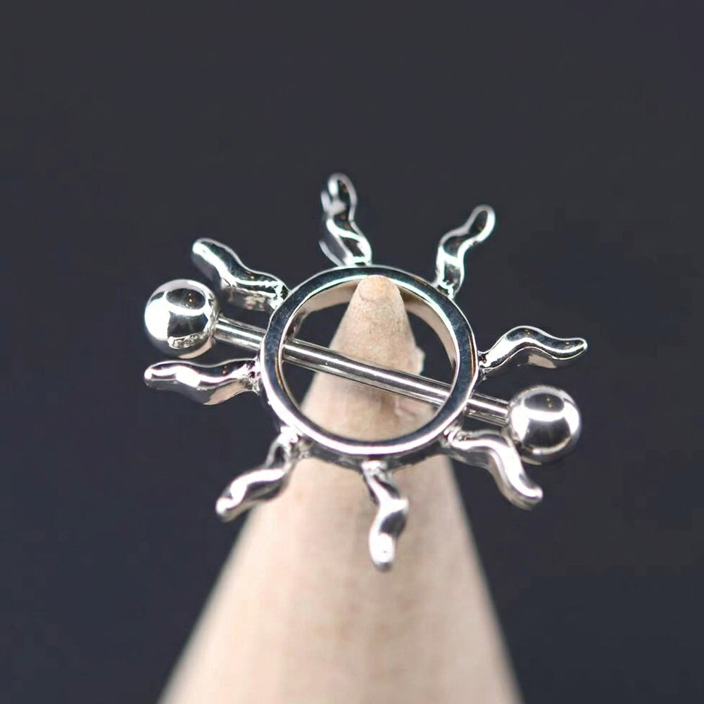 Detailed close-up angle shot of the sunburst nipple shield seen in image_9.png and image_10.png, resting on a textured wooden or ceramic cone display, highlighting the three-dimensional metal craftsmanship.