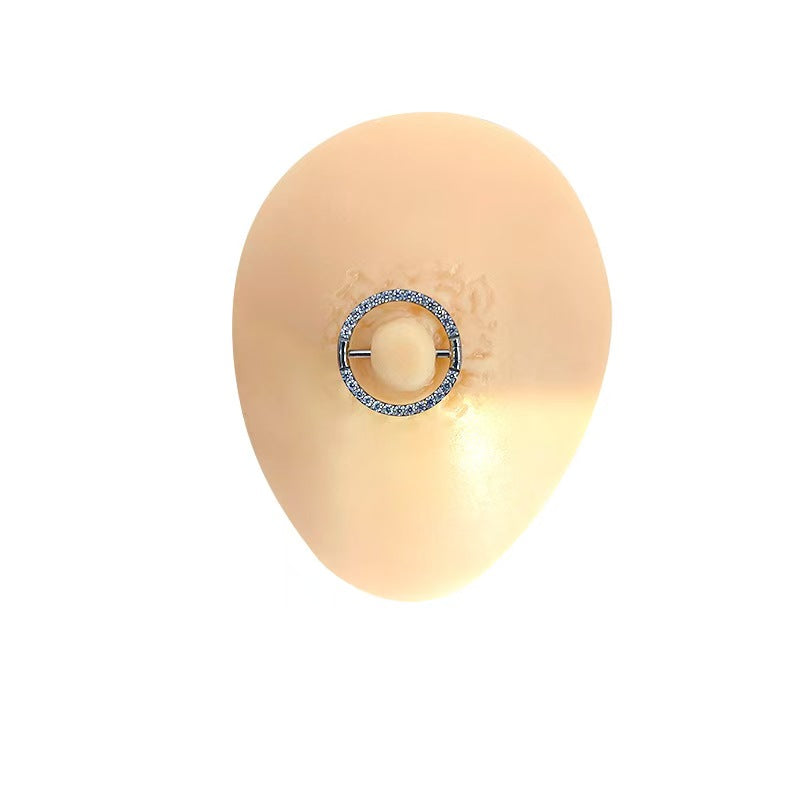 A sparkling crystal paved silver F136 titanium nipple shield ring displayed on a silicone piercing mannequin.