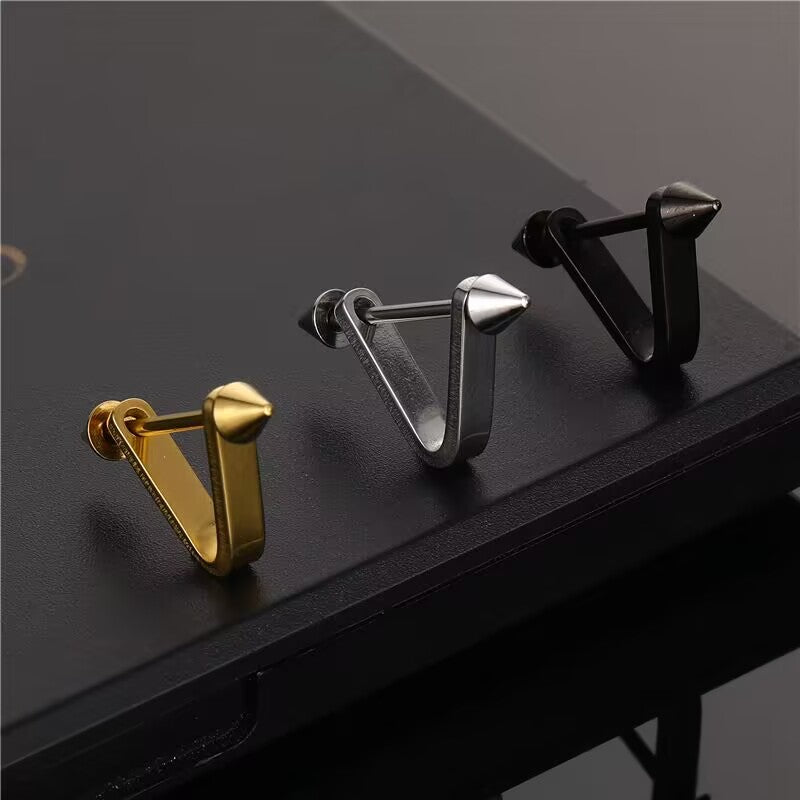 Three color variants of V-spike cartilage stud earrings resting on a dark surface