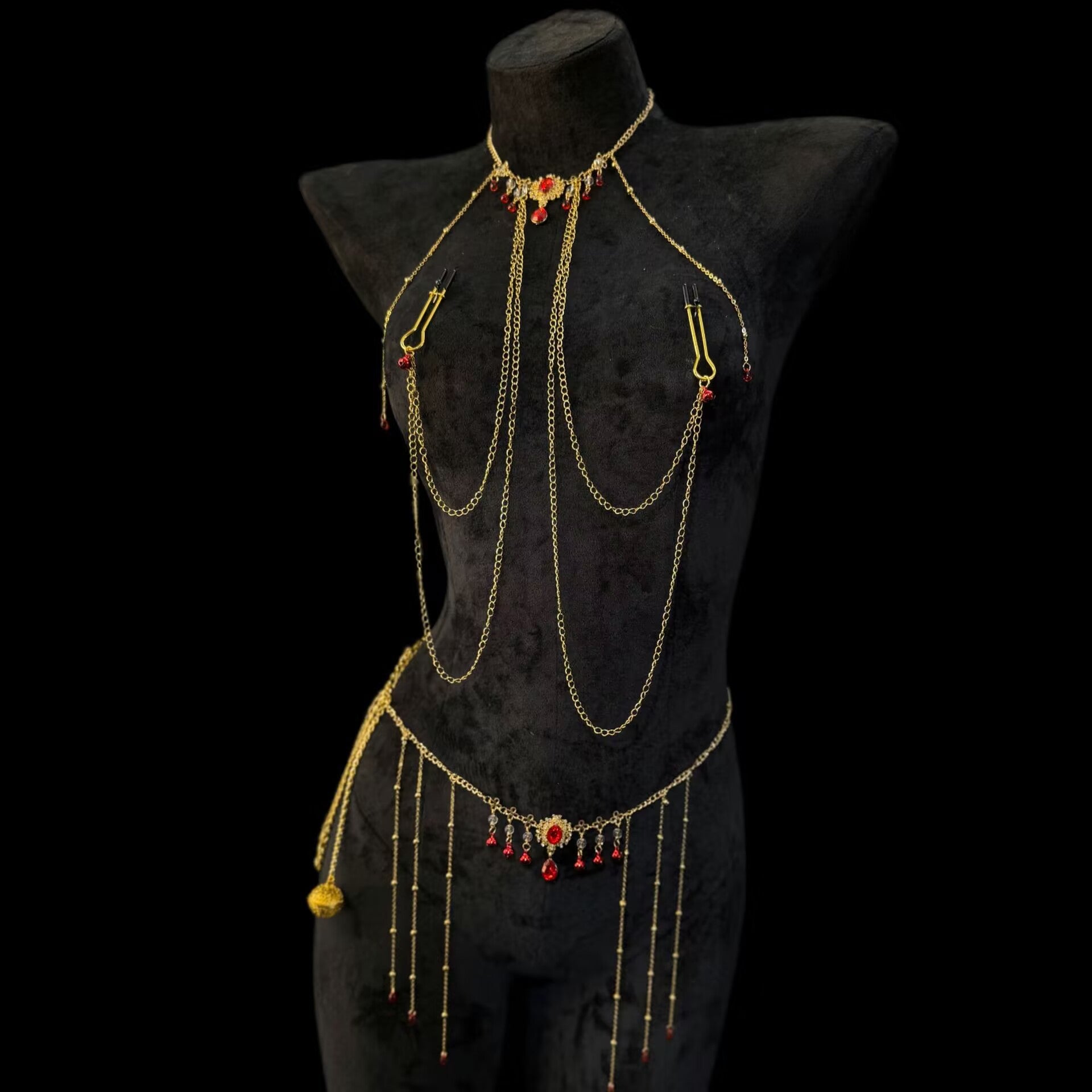 Connected gold body jewelry featuring vintage ruby pendants and sleek shepherd hook clamps on a black mannequin.