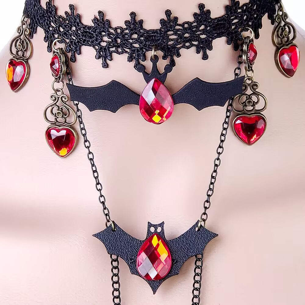 Detailed view of gothic vampire style bat charm with ruby red drop crystal attached to lace choker.