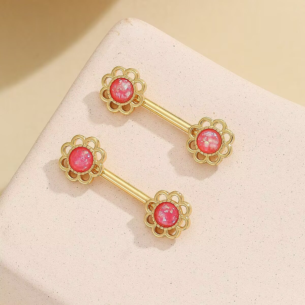 Pair of gold-tone flower faux nipple rings with vibrant shimmering pink centers.