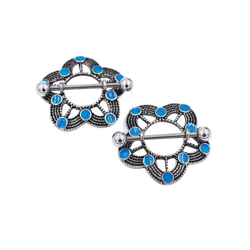 Close-up shot of an antique silver nipple shield with a floral mandala pattern and vibrant turquoise-blue enamel dots.
