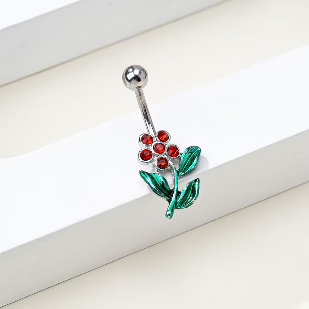 Detailed close-up view of the 5-gem red rhinestone flower and green leaf pendant on a curved belly piercing bar.