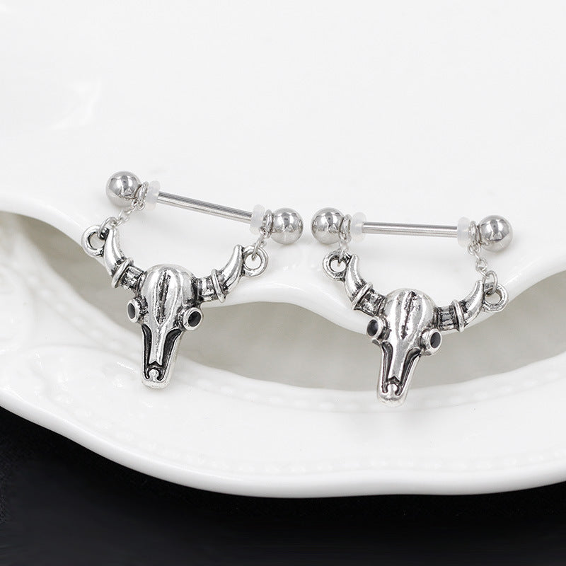 A pair of vintage silver ox skull nipple shields resting on a white decorative ceramic plate