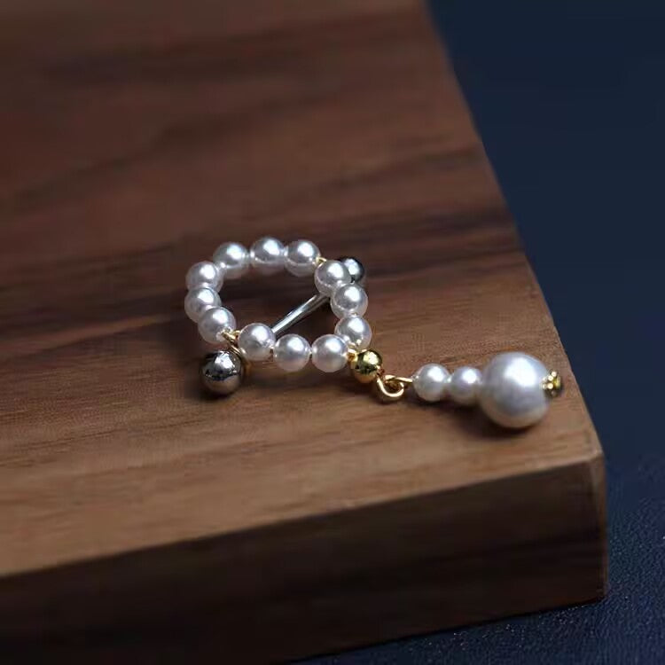 Detailed view of a white pearl nipple shield with hanging pearl pendant.